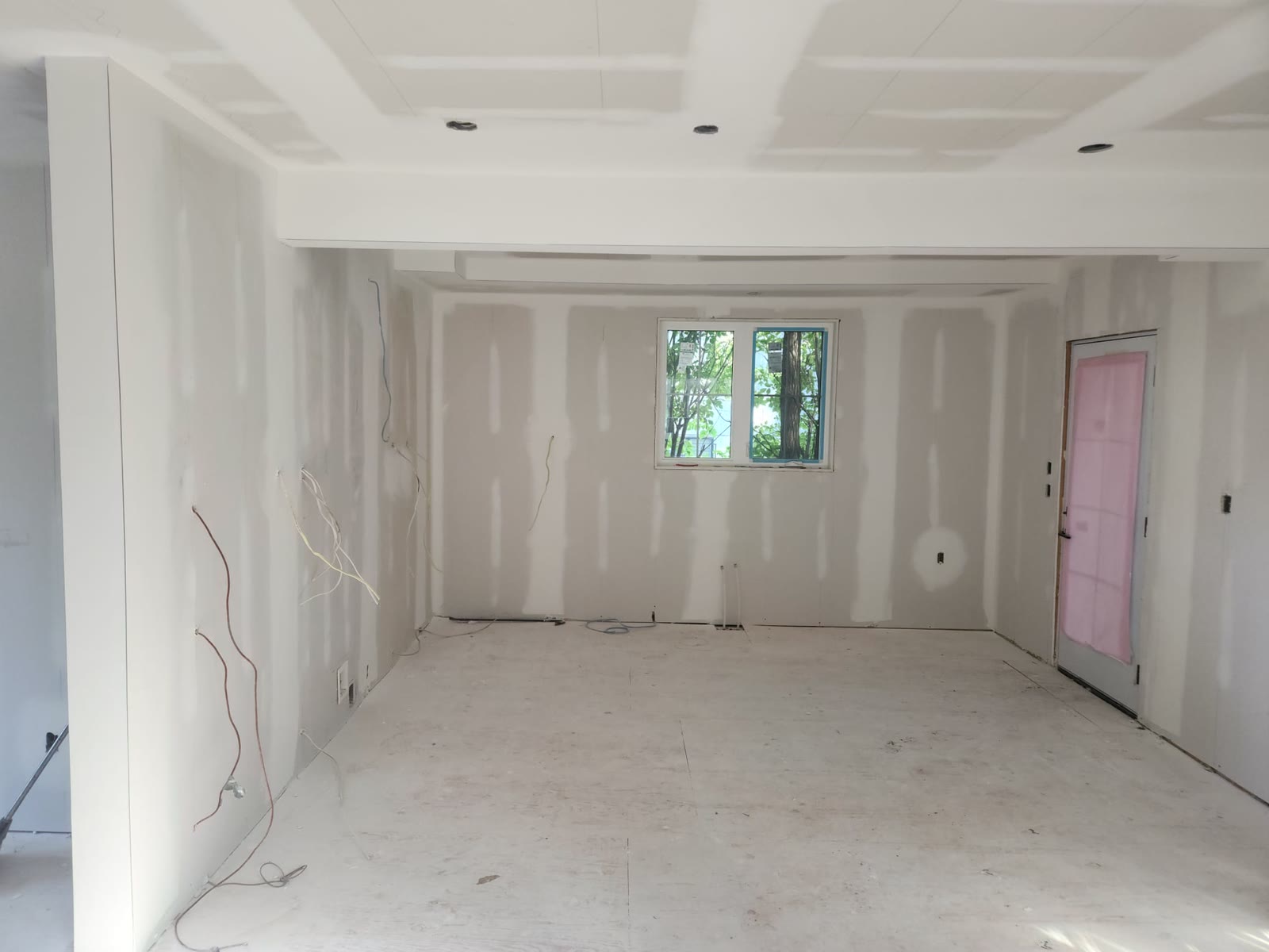 Renovated room with taped and mudded drywall joints on the walls, coffered ceiling and bulkhead, before sanding